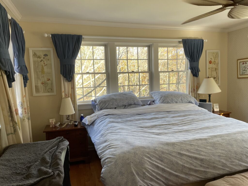 Before view of a primary bedroom showing natural light, empty walls, and an unlayered layout.